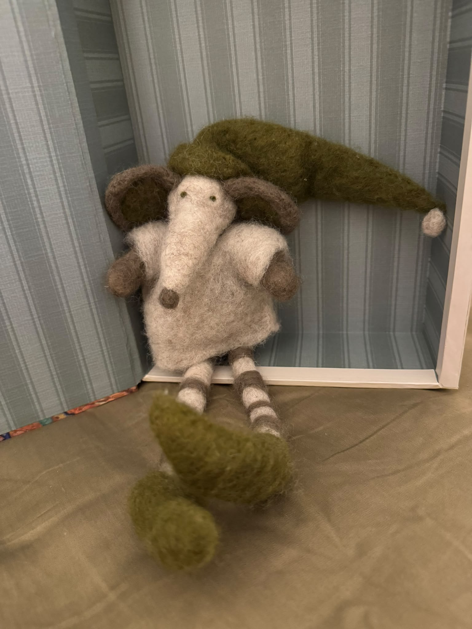 Ein handgefilzter Elefant mit langer grüner Wichtelmütze