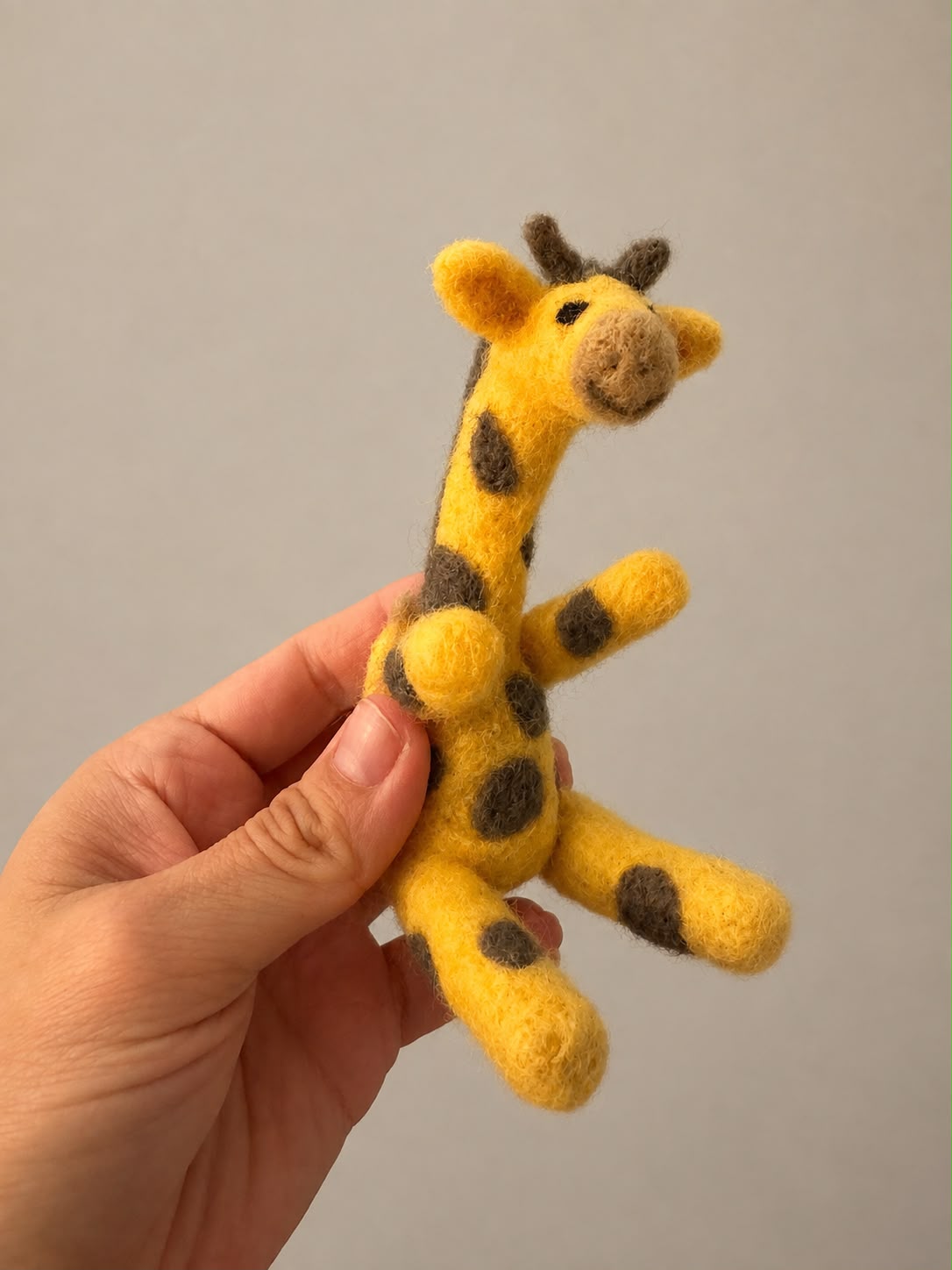 Eine handgefilzte Giraffe zwischen Blumen