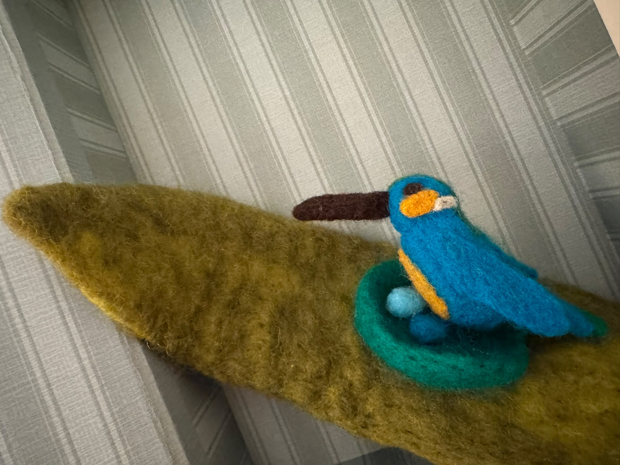 Ein türkiser Filzvogel in einem kleinen Nest
